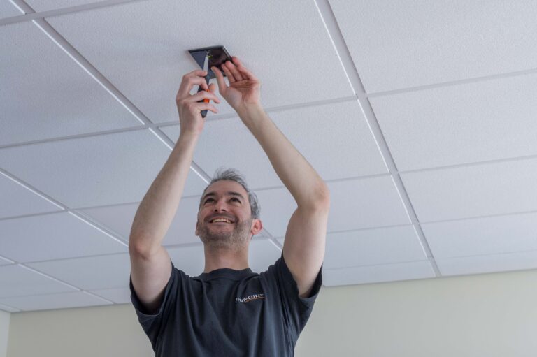 A pinpoint engineer installing a Pinpoint System to the ceiling of a room.