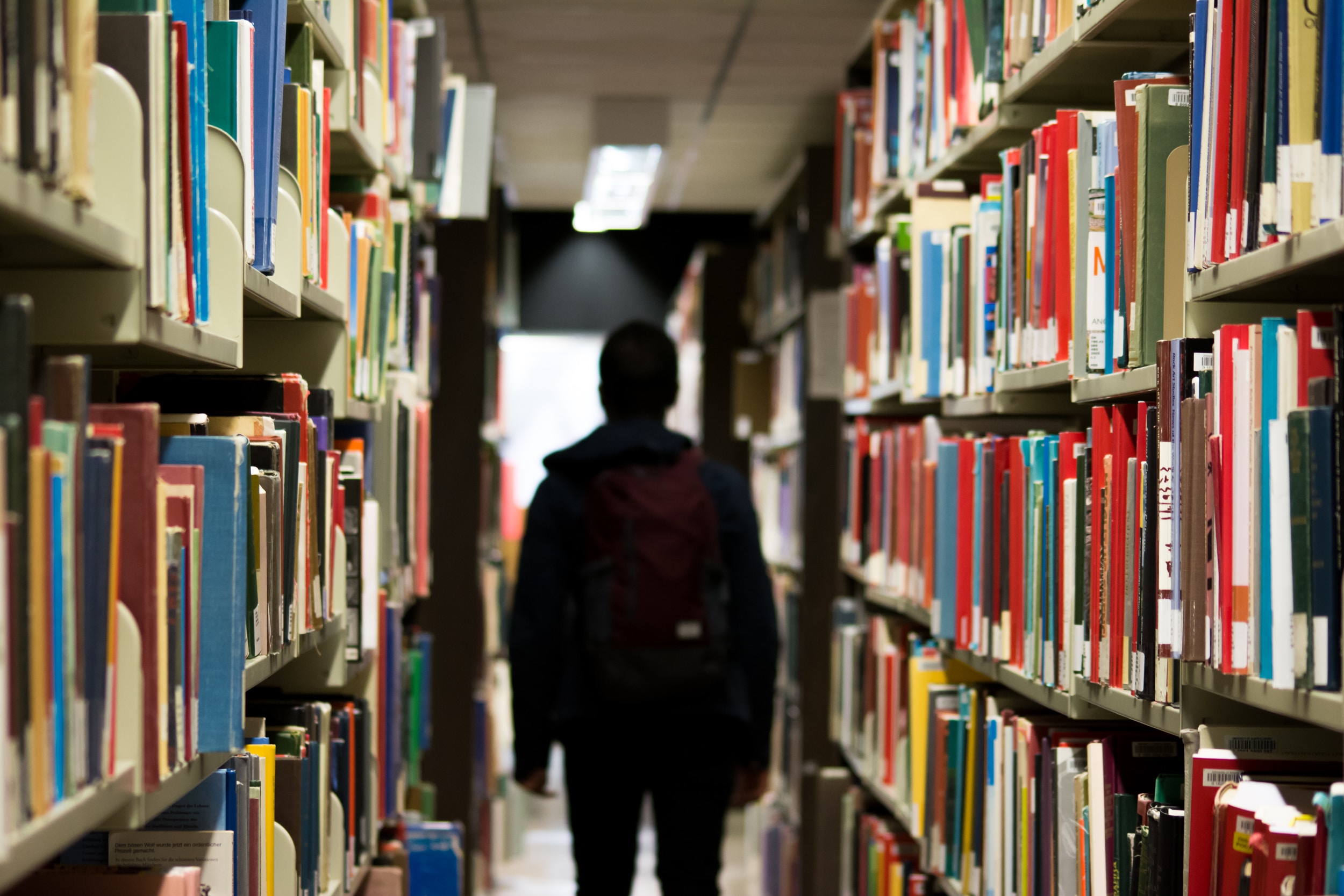 Student walks between bookshelves