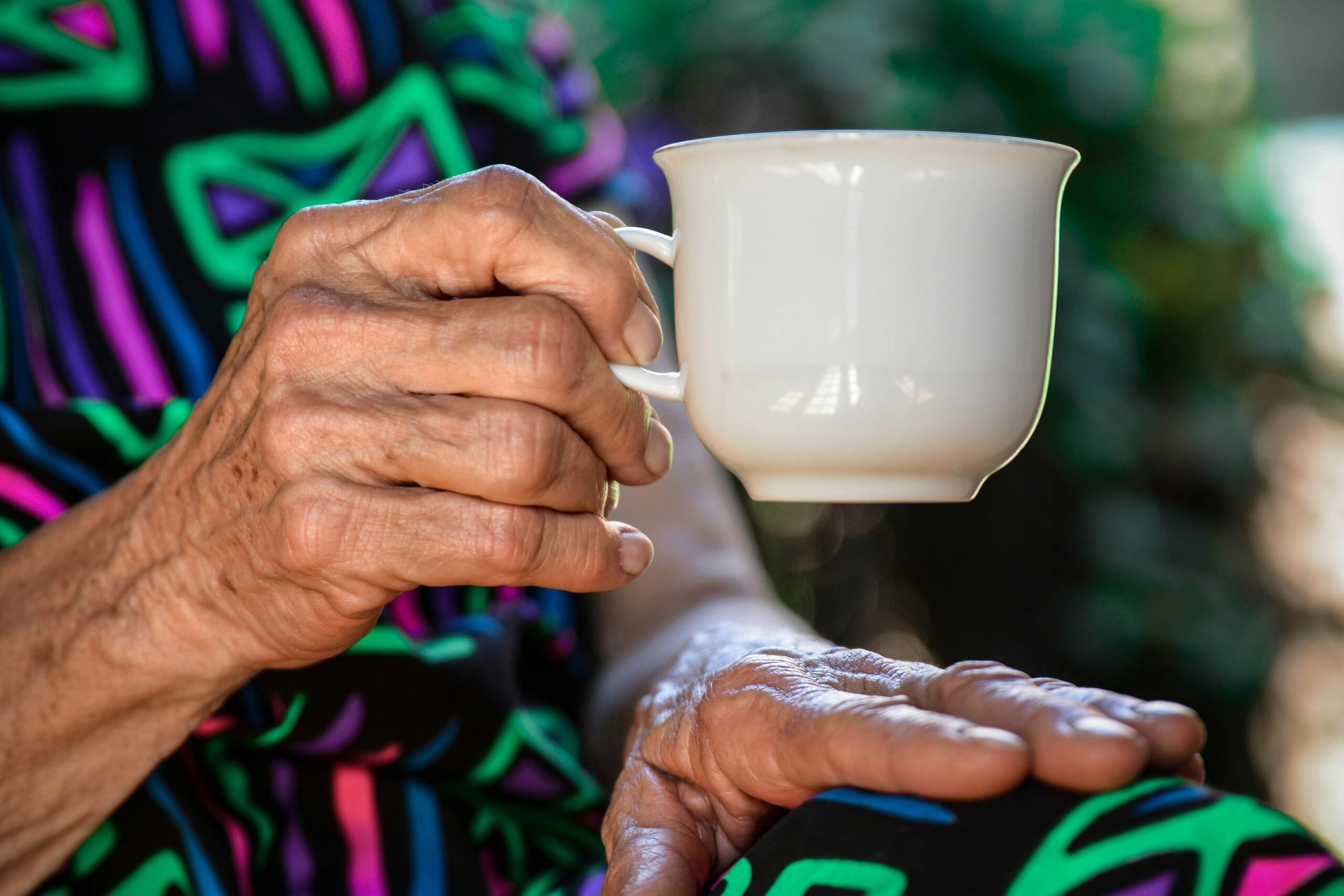 Elderly hand holds cup of tea